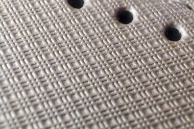 Örgü desenli dokuma kumaşın yakın çekimi ve karmaşık tasarım ve yapıyı gösteren delikler. Tekstil ile ilgili projelerde arka plan veya detay için ideal.