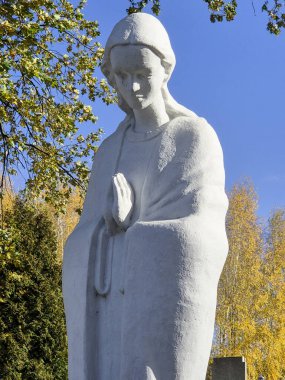 Huzurlu, beyaz bir heykel. Huzurlu bir ortamda, renkli sonbahar yapraklarıyla çevrili.