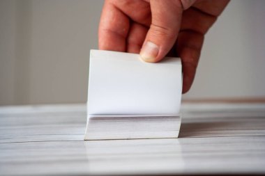 Yaratıcılığı ve fikirleri sembolize eden boş bir not defterini karıştıran bir el. Not defteri konsept ile ilgili görüntüler için ideal, rustik ahşap bir masa üzerine yerleştirilmiş..