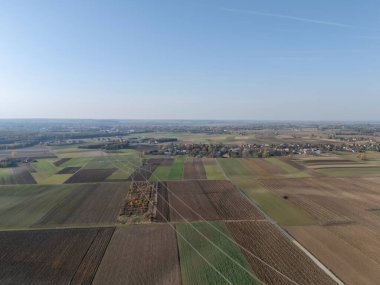 Açık mavi gökyüzü altında çeşitli yama şekilleri olan manzaralı tarımsal alanlar doğanın ve tarım arazilerinin güzelliğini gösteriyor..