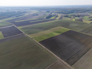 Doğanın ve tarım arazilerinin güzelliğini gösteren yeşil ve kahverengi tonlarıyla uçsuz bucaksız tarım alanları..