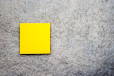 Yumuşak desenli bir yüzeye yerleştirilmiş canlı sarı yapışkan bir nota. Bu minimalist görüntü yaratıcılığı ve organizasyonu ofis veya çalışma ortamları için mükemmel hale getiriyor..