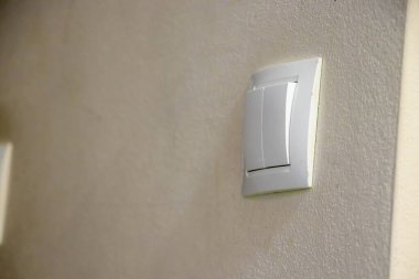 Modern bir ışık düğmesinin, dokulu bir duvar vitrininin minimalist tasarımı üzerine yakın plan çekimi. İç tasarım ve ev geliştirme projeleri için ideal.