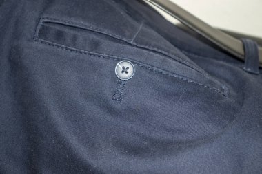 Kumaş bir gömleğin üzerindeki mavi düğmeye yakın çekim, desen ve detay içeriyor. Moda ve giysi malzemeleri için ideal.