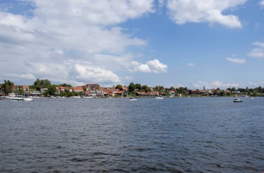 Mikolajki Polonya - 29 Eylül 2024: Mikolajki 'nin sudaki yemyeşil ve yaz bulutlarıyla çevrili manzarası.