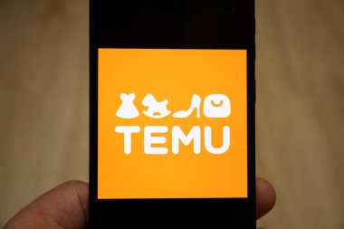 Varşova Polonya - 17 Ocak 2025: Temu logosu modern alışveriş ve e-ticareti sembolize eden bir akıllı telefon üzerinde sergilendi. Canlı turuncu arkaplan marka tanıma ve cazibesini artırıyor.