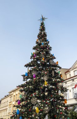 Rzeszow Polonya - 19 Ocak 2025: Güzel dekore edilmiş bir Noel ağacı açık bir gökyüzüne karşı renkli süsler ve ışıklarla parıldayan bir şehir meydanında dimdik duruyor.