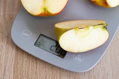 Dijital ölçekte taze elma dilimleri sağlıklı beslenme kavramları için ideal ağırlığı gösteriyor. Beslenme ve tazeliği vurgular.