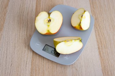 Mutfak tartısında taze elma dilimleri. Sağlık ve beslenme kavramları için idealdir. Parlak renkler ve doğal ışık tazeliği vurgular.