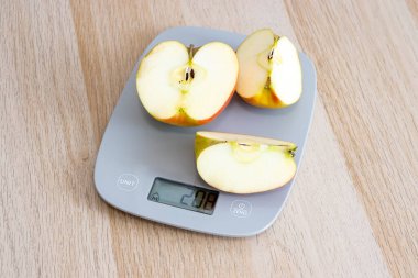 Dijital mutfak terazisinde taze elma dilimleri sağlıklı beslenme ve kilo yönetimini vurguluyor. Sağlık blogları ve yemek rehberleri için ideal.