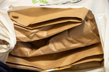 Naylon bir poşetin içinde düzgünce istiflenmiş kahverengi kağıt torbaların desen ve rengini gösteren bir yakın plan. Sürdürülebilirlik veya alışveriş temaları için ideal.