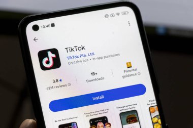 Varşova Polonya - 10 Mart 2025: TikTok uygulama arayüzünü gösteren telefon, mobil kullanıcıların reytinglerini ve indirme seçeneklerini vurguluyor. Teknolojiyle ilgili görseller için ideal.