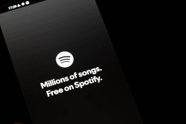 Varşova Polonya - 10 Mart 2025: Spotify uygulamasını gösteren bir akıllı telefon dijital müzik tüketimini ve erişilebilirliği vurgulayan milyonlarca şarkıya serbest erişim sloganını sergiliyor.