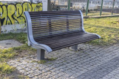 Güneşli bir günde modern park bankında yeşil çimlerin yanında şehir manzarası ve arka planda graffiti sanatı dinlenmek için idealdir.