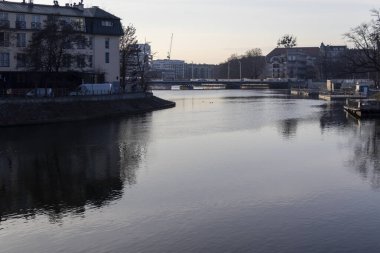 Şafak vakti binaların yansımasıyla sakin nehir manzarası Wroclaw Polonya kentsel doğanın dingin güzelliğini yakalıyor..