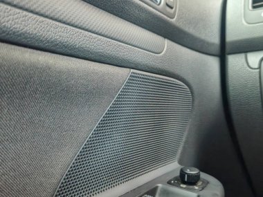 Bir hoparlörü gösteren ve otomotiv meraklıları için tasarım ve işlevselliği vurgulayan desenli bir iç mekanın yakın görüntüsü.