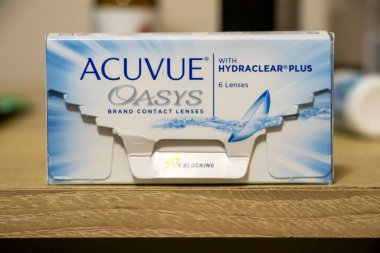 Varşova Polonya - 19 Ocak 2025: Acuvue Oasys kontak lens kutusu günlük kullanım için konfor ve görüş netliğini vurgulayan ahşap bir yüzey üzerinde sergilendi.