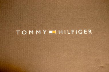 Varşova Polonya - 19 Ocak 2025: Tommy Hilfiger logosu lüks ve modern modayı sembolize eden kahverengi bir arka planda sergilendi.