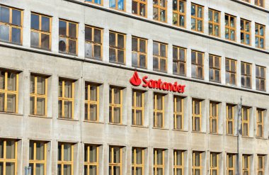 Wroclaw Polonya - 21 Şubat 2025: Santander Bank binasında belirgin kırmızı logosu ve kentsel tarzı yansıtan çok sayıda penceresi olan modern mimari yer alıyor.