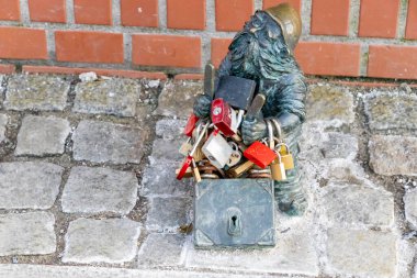 Wroclaw Polonya - 21 Şubat 2025: Cüce heykeli, Tumski yakınlarında bir tuğla duvara karşı asma kilitlerle dolu bir kutu tutuyor