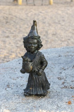 Wroclaw Polonya - 21 Şubat 2025: Cüce heykeli neşeli bir park ortamında bir bebek cüce tutuyor