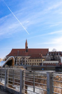 Wroclaw Polonya - 23 Şubat 2025: Wroclaw nehri boyunca uzanan tarihi mimari manzarası bir kilise kulesi ve güzel mavi gökyüzü.