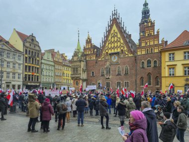 Wroclaw Polonya - 23 Şubat 2025: Bir şehir meydanında bayraklar ve pankartlar taşıyan bir halk gösterisi için tarihi binaların önünde kalabalık toplandı