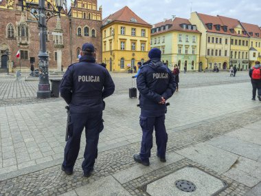 Wroclaw Polonya - 23 Şubat 2025: Şehir meydanında halk arasında güvenlik ve düzeni koruyan iki polis memuru. Şehir manzarası.