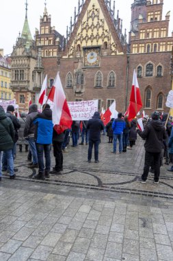 Wroclaw Polonya - 23 Şubat 2025: Vatandaşlar kışın sosyal değişimi savunan tarihi mimari önünde Polonya bayrakları taşıyorlar
