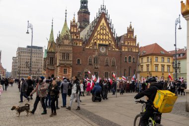 Wroclaw Polonya - 23 Şubat 2025: Arka planda bayraklar ve tarihi mimariyle kent meydanında barışçıl bir gösteriye katılan kalabalık.