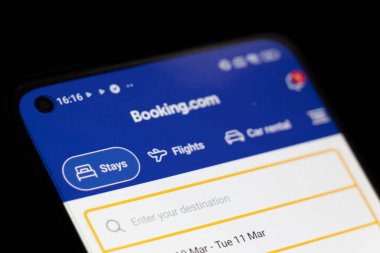 Varşova Polonya - 10 Mart 2025: Kalış ve uçuşlar için seçenekler sunan seyahat rezervasyonları için Booking.com ana sayfasını gösteren akıllı telefonun kapatılması.
