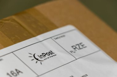 Varşova Polonya - 12 Mart 2025: InPost 'tan bir karton kutunun üzerindeki bir nakliye etiketinin e-ticarette lojistik ve ambalajı vurguluyor.
