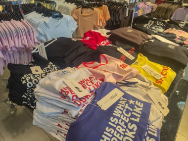 Przemysl Poland - Mart 12025: Perakende mağaza ortamında çeşitli tasarım ve ifadelerin yer aldığı canlı renkli tişörtler sergileniyor.