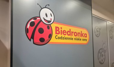 Rzeszow Polonya - 2 Mart 2025: Biedronka logosu, düşük fiyatları ve ulaşılabilirliği sembolize eden eğimli bir arka plana karşı dostça bir uğur böceği tasarımı sergiledi.