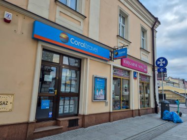 Rzeszow Polonya - 2 Mart 2025: Bir şehir caddesinde bulunan Coraltravel acentesi, canlı tabelası ve komşu kitapçıya seyahat hizmetleri sunuyor.
