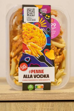 Varşova Polonya - 11 Mart 2025: Ahşap arka planda domates soslu makarna ve renkli grafikler içeren bir paket Penne alla Vodka menüsü.