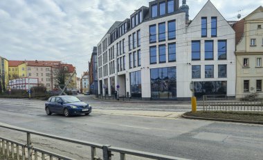 Wroclaw Polonya - 23 Şubat 2025: Modern bir araba, kentsel gelişimi canlı bir şekilde sergileyen şehirde çağdaş mimarinin yanından geçiyor.