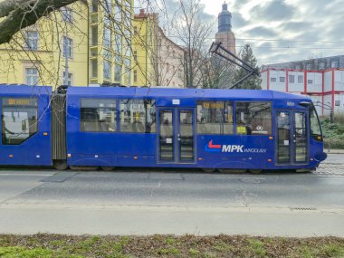 Wroclaw Polonya - 23 Şubat 2025: MPK Wroclaw 'ın mavi tramvayı arka planda ağaçlar ve binalar ile cadde boyunca park edilmiştir.