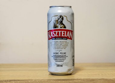 Varşova Polonya - 11 Mart 2025: Bir kutu Kasztelan birası özel etiketini ve eşsiz markasını gösteren ahşap bir masa üzerinde.