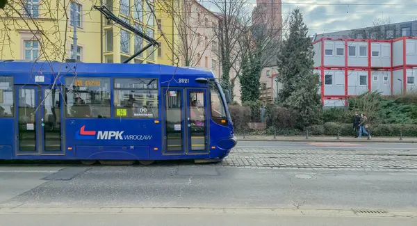 Wroclaw Polonya - 23 Şubat 2025: MPK tramvayı canlı bir şehirde kentsel taşımacılığı gözler önüne seren cadde boyunca konut binalarının önünden geçiyor.