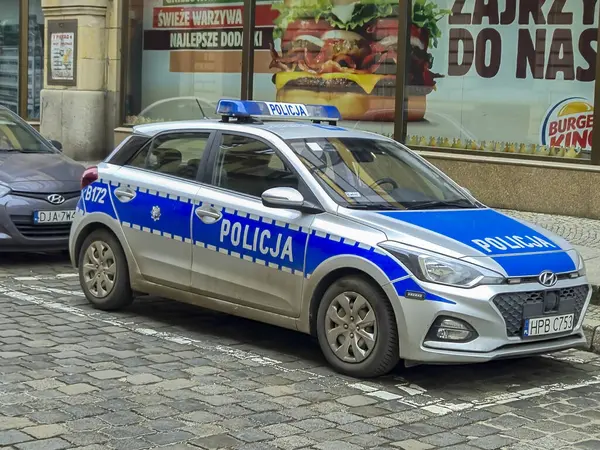 Wroclaw Polonya - 23 Şubat 2025: Polonya polis arabası, fast food tanıtımı için sokak reklam arkaplanına park edildi. Şehir güvenliği.