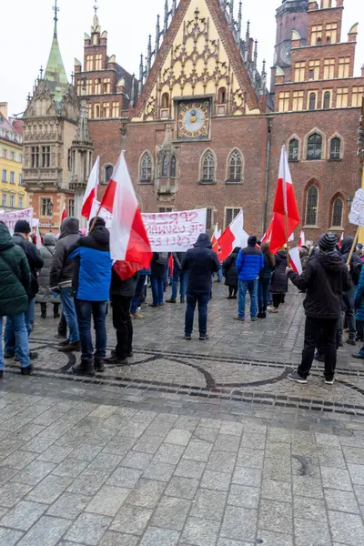 Wroclaw Polonya - 23 Şubat 2025: Vatandaşlar kışın sosyal değişimi savunan tarihi mimari önünde Polonya bayrakları taşıyorlar