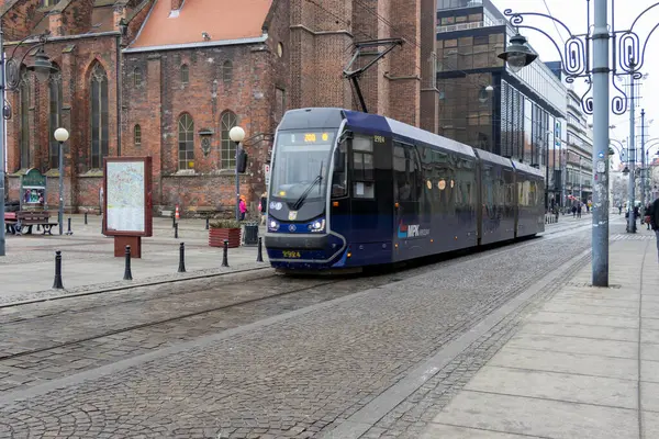 Wroclaw Polonya - 23 Şubat 2025: Wroclaw kentsel manzarası üzerinden yolcuları taşıyan tarihi binaların yakınındaki bir şehir caddesinde modern bir tramvay faaliyet gösteriyor.