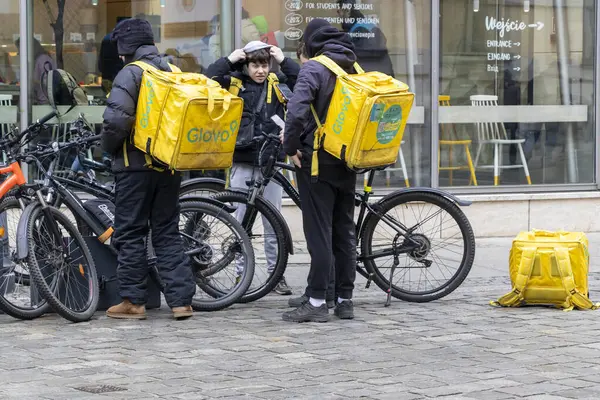 Wroclaw Polonya - 23 Şubat 2025: Teslimat binicileri bisiklet ve Glovo çantalarıyla yiyecek teslimatına hazırlanan şehir ortamında bir araya geldiler.
