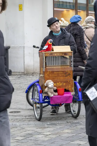 Wroclaw Polonya - 23 Şubat 2025: Sokak müzisyeni elle kumandalı bir org eşliğinde renkli oyuncaklar sergiliyor ve yoldan geçenleri canlı bir şehir atmosferine çekiyor.