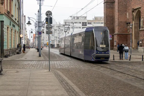 Wroclaw Polonya - 23 Şubat 2025: Wroclaw sokaklarındaki modern tramvay bulutlu bir günde tarihi binalar ve kentsel yaşamla çevrili