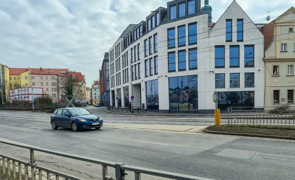 Wroclaw Polonya - 23 Şubat 2025: Modern bir araba, kentsel gelişimi canlı bir şekilde sergileyen şehirde çağdaş mimarinin yanından geçiyor.
