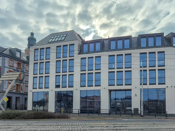 Wroclaw Polonya - 23 Şubat 2025: Gökyüzü bulutlu şehir gelişimi ve tasarımı sergilenen cam cepheli modern mimari yapı.