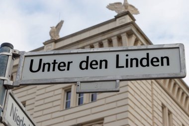 Berlin 'de bulunan Unter den Linden' ın sokak tabelası tarihi mimariyi gözler önüne seriyor. Tabela, klasik bir binanın davetkar keşfine karşı belirgin bir şekilde gösteriliyor.