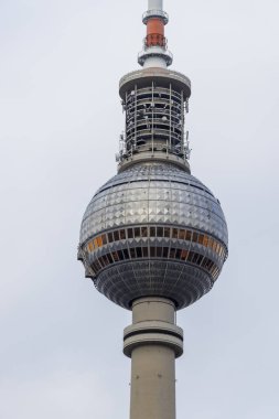 Berlin TV Kulesi bulutlu bir gökyüzünün altında küresel bir gözlem güvertesiyle ikonik tasarımını sergiliyor. Berlin Almanya 'sında merkezi bir dönüm noktası olarak hizmet vermektedir..